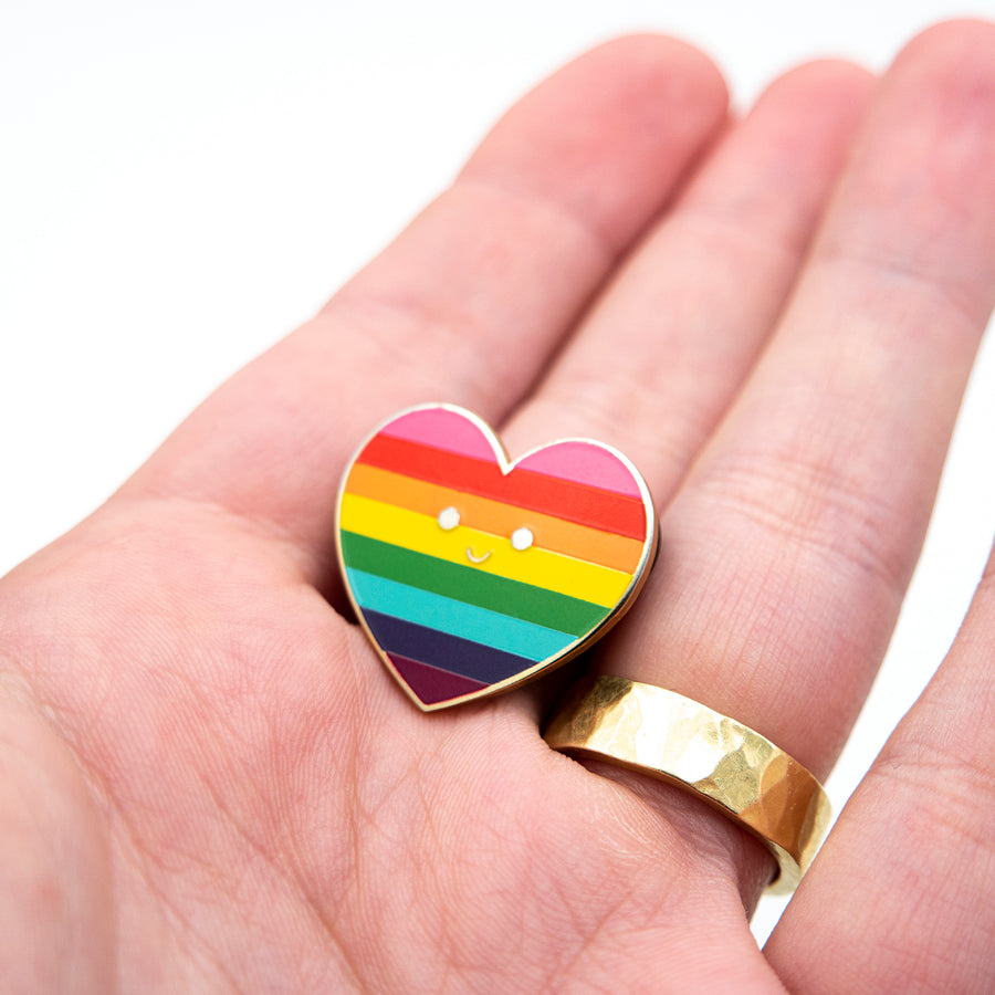 Gold-plated enamel pin displaying the Pride flag with vibrant colors symbolizing different aspects of life, healing, sunlight, nature, magic, harmony, and spirit.