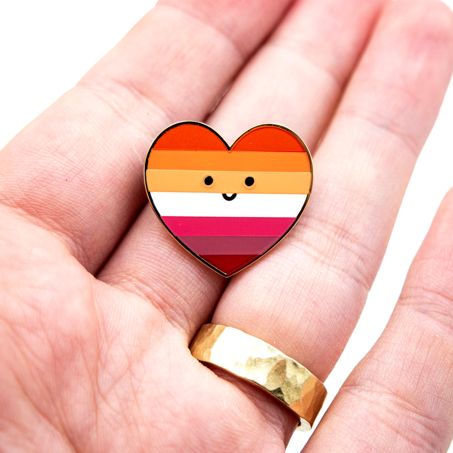 New lesbian pride flag features orange stripes, each representing gender non-conformity, independence, community, unique womanhood, serenity, love, and femininity.Lesbian pride flag enamel pin: 1